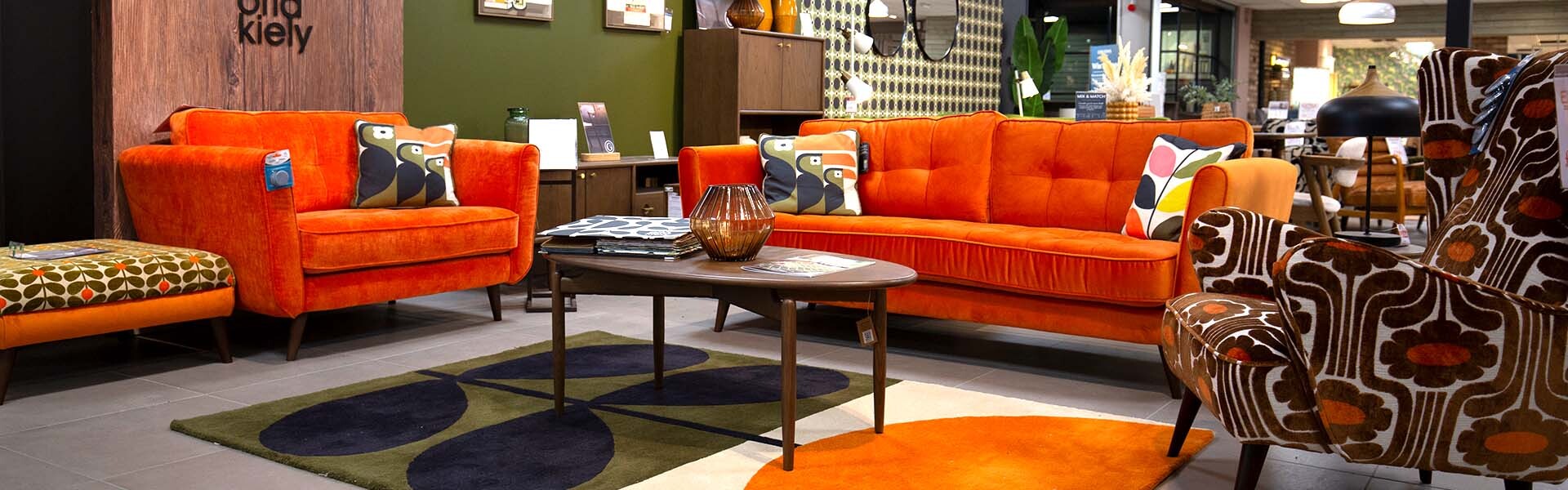 Orange velvet sofas and a retro patterned armchair styled in a Cousins showroom